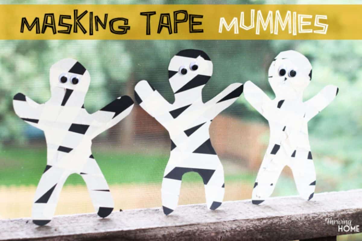 Three masking tape mummies on a railing.