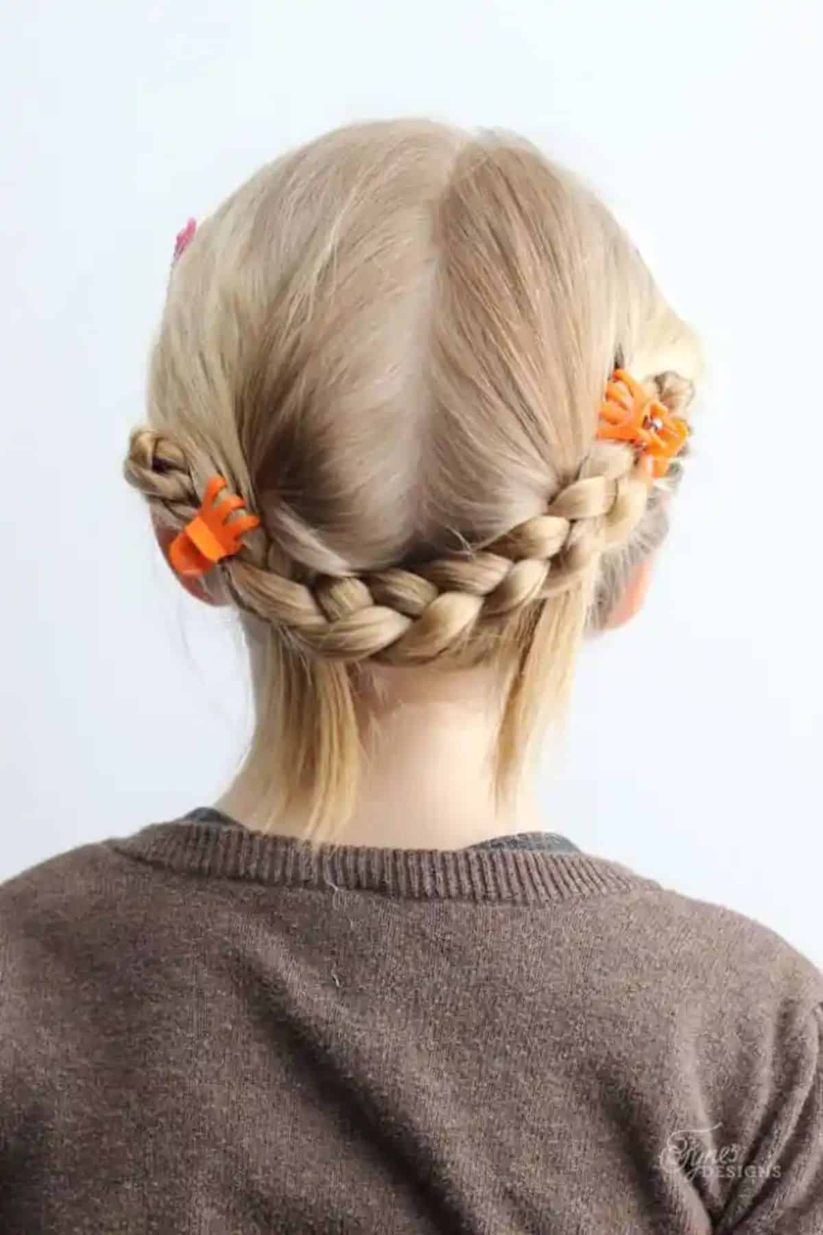 Young girl with a ponytail and orange hair clips.