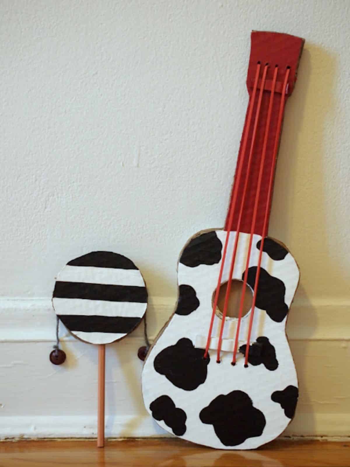 Cow themed cardboard guitar leaning on a wall.