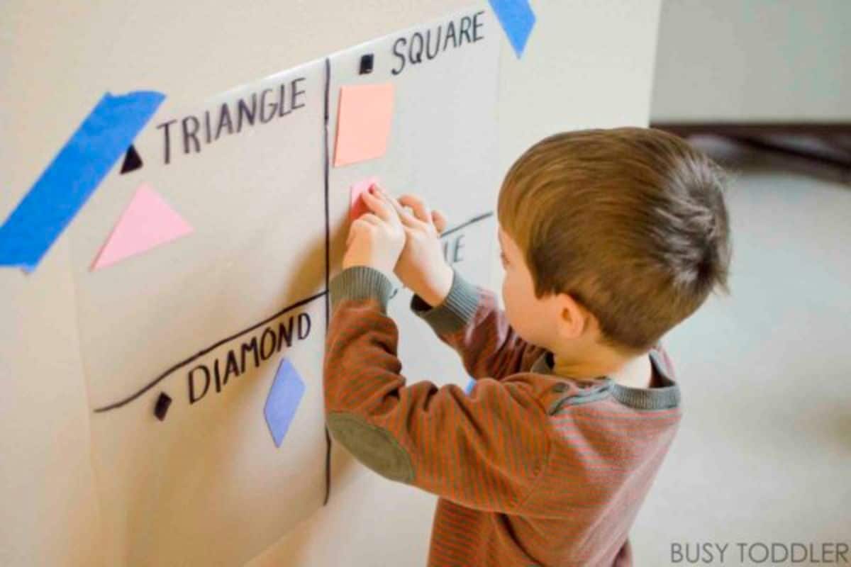 Young boy sticking notes on a wall.