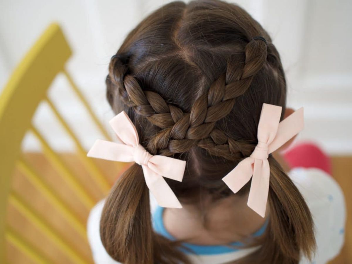 Young girl with ponytails and cream ribbons.