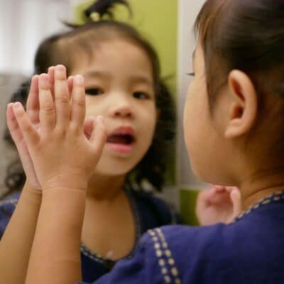 Young girl watching herself in a mirror.