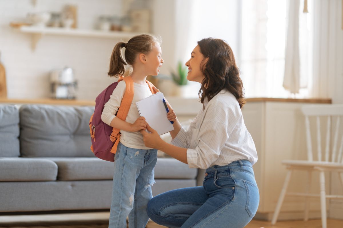 Young mother talking to her daughter before leaving for a school.