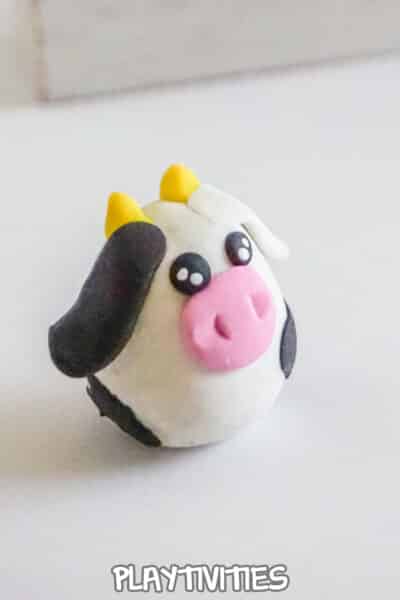 closeup of a tiny kawaii cow charm for a necklace made of polymer clay